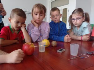 grupa dzieci pokazuje przybory do eksperymentu