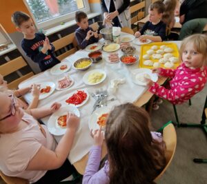 Dzieci przygotowują swoją własną pizzę.