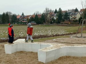 dwóch chłopców chodzi po betonowej ławce