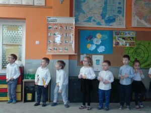grupa przedszkolaków stoi w sali przedszkolnej