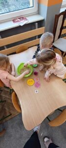 dzieci segregują ukryte przedmioty w misce wypełnionej grochem