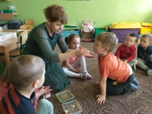 dzieci i nauczycielka siedzą w kole, chłopiec próbuje cytryny