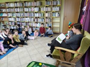 Pani bibliotekarka czyta dzieciom książkę w bibliotece.