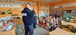 Na zdjęciu dzieci słuchające policjantów, oraz policjanci prowadzący rozmowę.