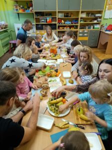 rodzice pomagają swoim dzieciom przy robieniu sałatki owocowej i jeżyków sałatkowych