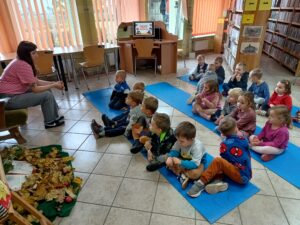 Dzieci siedzą na niebieskich matach w bibliotece