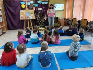 Dzieci słuchają bajki czytanej przez panią w bibliotece