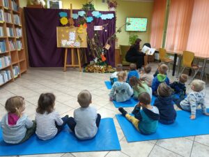 Dzieci słuchają bajki czytanej przez panią bibliotekarkę