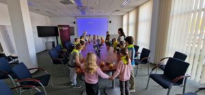 Dzieci stoją dookoła stołu i trzymają się za ręce