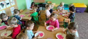 Dzieci malują papierowe talerze na różowo