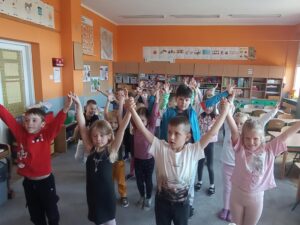 grupa dzieci stoi i podnosi ręce