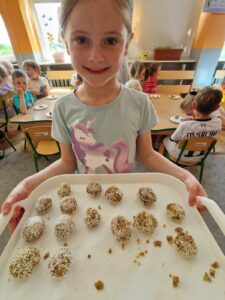 Dziewczynka pokazuje kulki z suszonych owoców i orzechów.