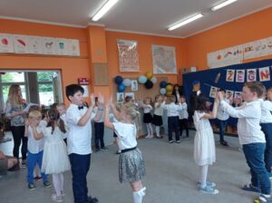 grupa dzieci tańczy na dywanie w sali