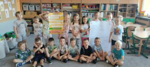 Dzieci pozują do zdjęcia grupowego z plakatami dotyczącymi bezpieczeństwa