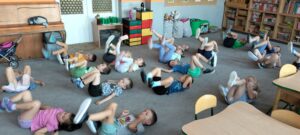 Dzieci leżą na dywanie i robią rowerek