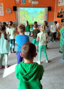Dzieci robią rozgrzewkę powtarzają ruchy z tablicy interaktywnej