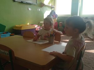 dwie dziewczynki rysują przy stolikach