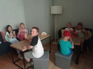 grupa dzieci siedzi w cukierni i je lody