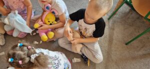 Chłopiec przykleja misiowi plaster z opatrunkiem.