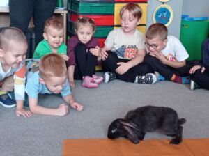Królik biega na dywanie pośrodku koła dzieci
