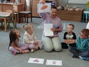 Nauczycielka prezentuje ilustracje z chlebem, rolnikiem i piekarzem