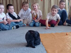 Królik biega na dywanie pośrodku koła dzieci