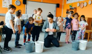 Dzieci stoją w rzędzie, prowadzący tłumaczy im ich zadanie