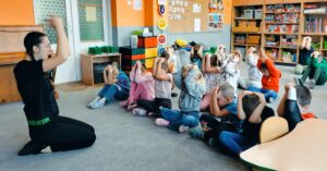 Dzieci siedzą na dywanie i uczą się ochraniać głowę