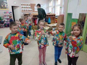 grupa dzieci w fartuszkach trzyma eksperyment w ręku