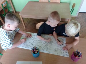 troje dzieci koloruje wspólną kolorowankę
