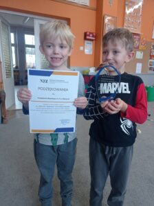 jeden chłopiec trzyma dyplom, drugi statuetkę