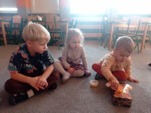 troje dzieci na dywanie, chłopiec ma w ręku łyżkę