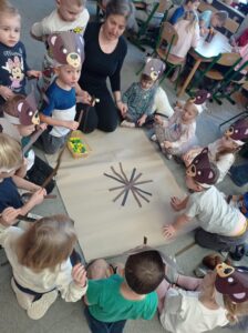 grupa dzieci z nauczycielem wykonuje pracę plastyczną