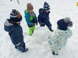 czworo dzieci lepi kulę śnieżną