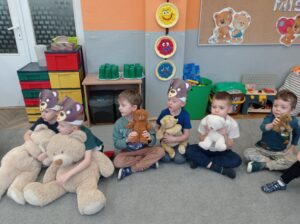 czterech chłopców siedzi na dywanie, trzymają w rękach misie