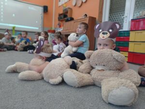 dzieci siedzą na dywanie z misiem