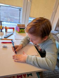 Chłopiec pisze życzenia na kartce