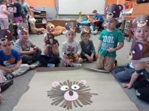 kilkoro dzieci siedzi za misiem wykonanym z pasków