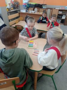 troje dzieci liczy kolorowe patyczki