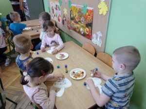 dzieci przy stolikach tworzą obrazki