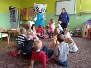 dzieci siedzą na dywanie, pracownik księgarni stoi, obok niego Kicia Kocia