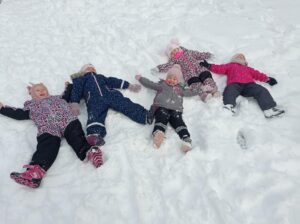 grupa dzieci robi aniołki na śniegu