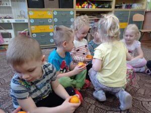 dziewczynka rozdaje dzieciom mandarynki