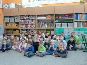 grupa dzieci siedzi na dywanie w sali