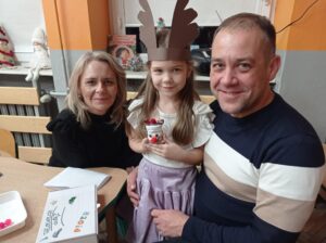 tata, mama i dziewczynka pokazują renifera