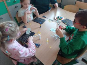 dzieci przy stoliku wycinają elementy pracy