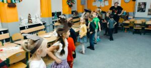 dzieci w opaskach reniferów tańczą na dywanie