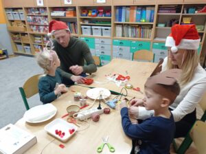 rodzina siedzi przy stole i wykonuje renifera