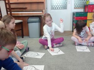 kilkoro dzieci wodzi palcem po obrazku bombki