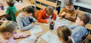 Dzieci przy stolikach kolorują aniołki